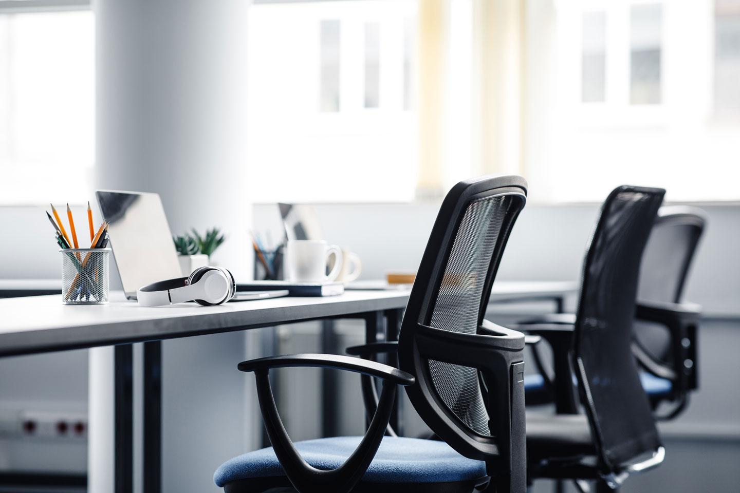 An open office showing a row of chairs and laptops ready for workers to return